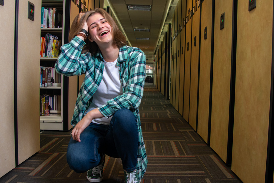 student Claire Bowman 25C squats down in the Woodruff Library